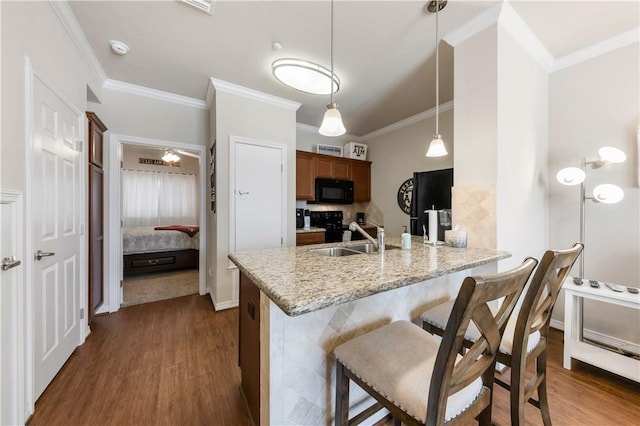 1198 Jones Butler Rd Unit 3103, College Station, TX 77840 - kitchen featuring black microwave, a sink, a peninsula, dark wood-type flooring, and ornamental molding