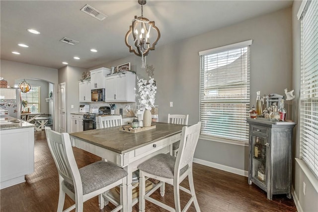 dining area featuring an inviting chandelier, sink, and dark wood-type flooring