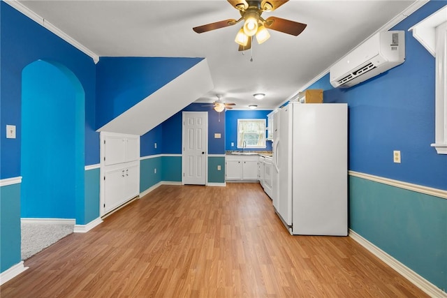 additional living space featuring an AC wall unit, ceiling fan, sink, and light wood-type flooring