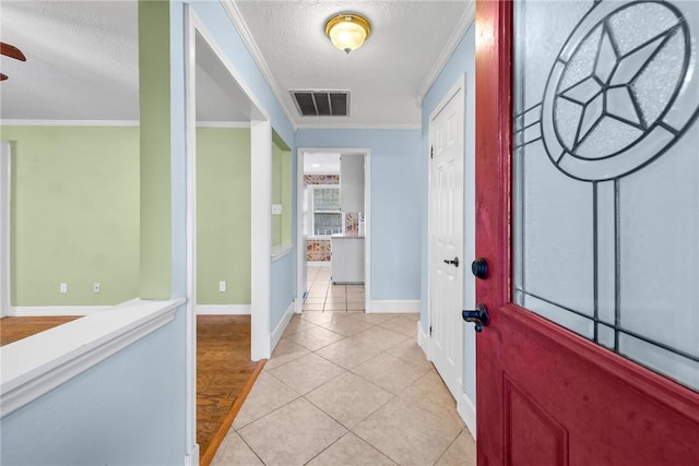 tiled foyer with a textured ceiling and crown molding