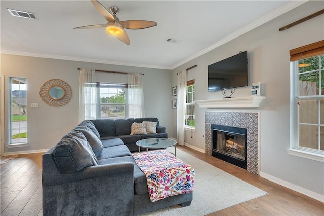 1905 Kingsgate Dr, Bryan, TX 77807 - living room featuring wood finished floors, ornamental molding, ceiling fan, a tile fireplace, and baseboards
