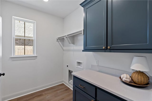washroom with baseboards, washer hookup, wood finished floors, hookup for an electric dryer, and cabinet space