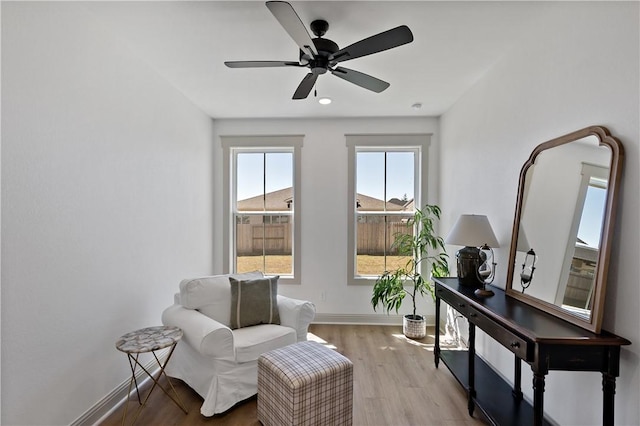 living area featuring baseboards, ceiling fan, and wood finished floors