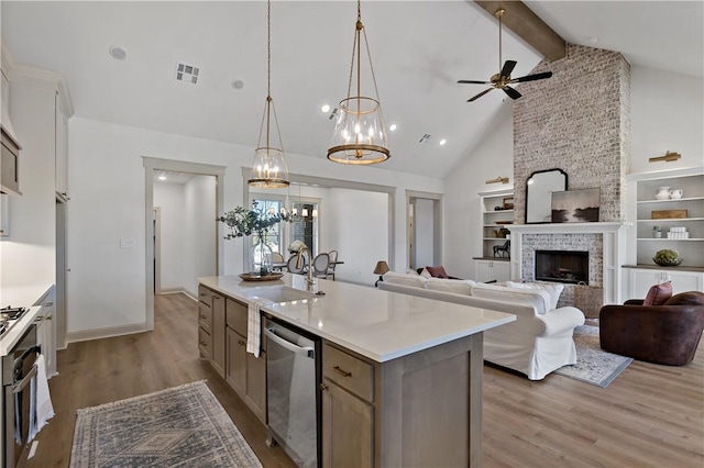 kitchen featuring stainless steel dishwasher, a sink, light wood-style floors, light countertops, and beam ceiling