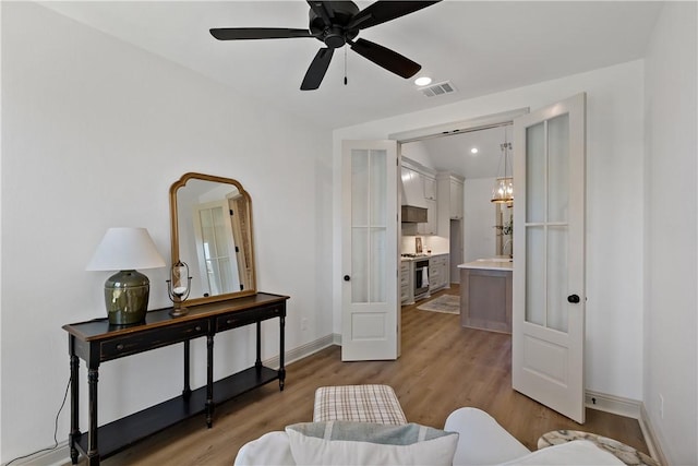 sitting room with ceiling fan with notable chandelier, light wood-type flooring, visible vents, baseboards, and recessed lighting
