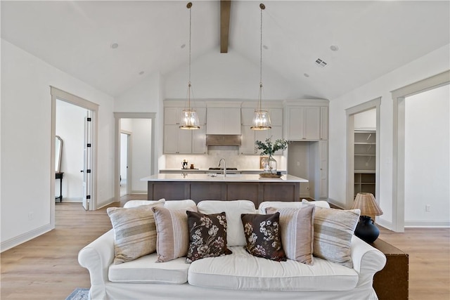 living area with light wood-type flooring, baseboards, beam ceiling, and high vaulted ceiling