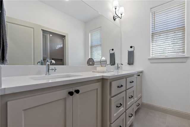 bathroom with baseboards, double vanity, and a sink