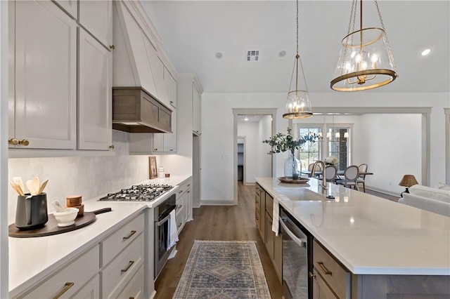kitchen featuring a sink, a spacious island, dark wood-type flooring, light countertops, and appliances with stainless steel finishes