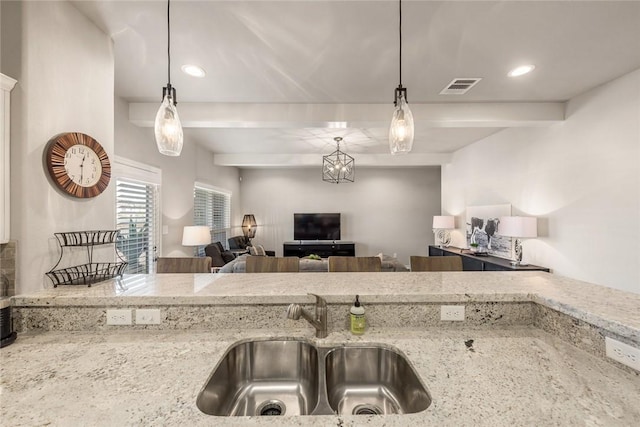 kitchen featuring light stone countertops, sink, and decorative light fixtures