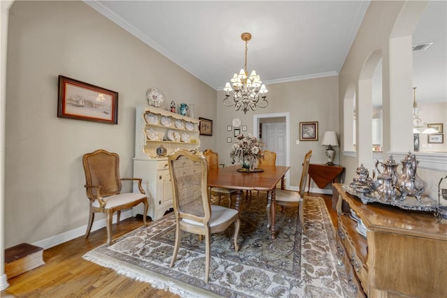 dining room featuring light wood-type flooring, ornamental molding, and an inviting chandelier