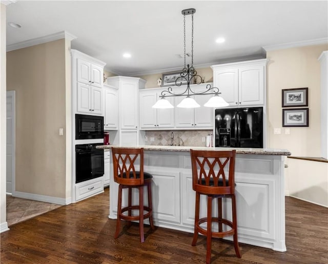 kitchen with decorative light fixtures, white cabinetry, a kitchen island, and black appliances