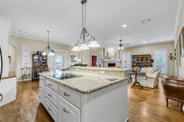 kitchen with dark hardwood / wood-style flooring, a center island, black electric stovetop, and a healthy amount of sunlight