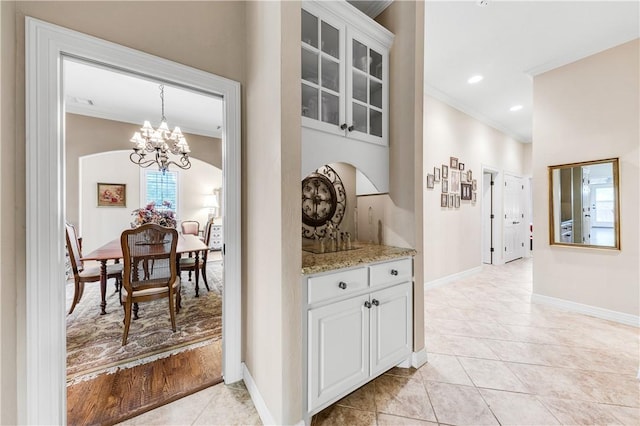 interior space featuring crown molding, light tile patterned floors, and an inviting chandelier