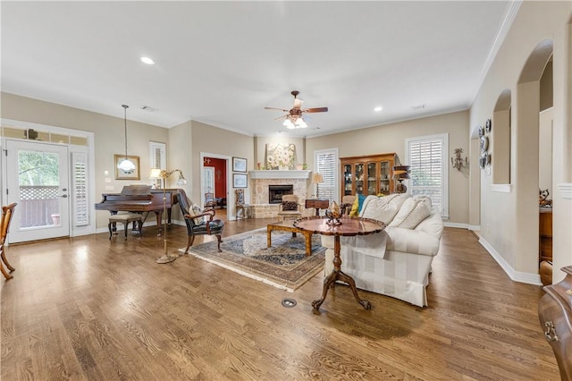 living room with wood-type flooring, ceiling fan, and ornamental molding