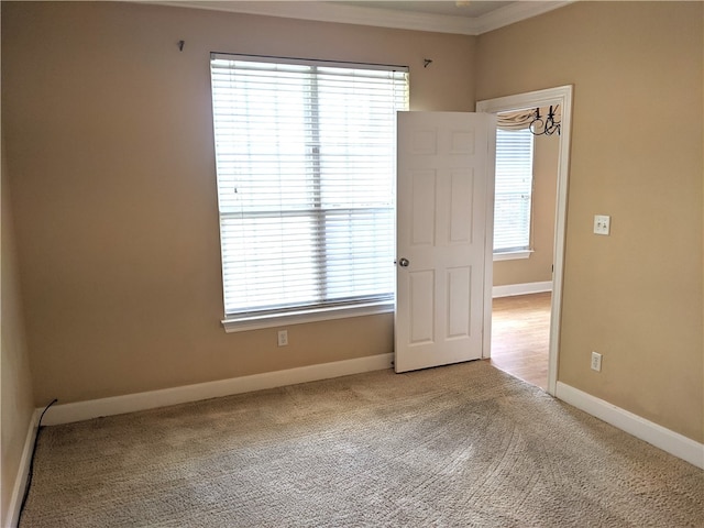 spare room with carpet floors, crown molding, and a chandelier