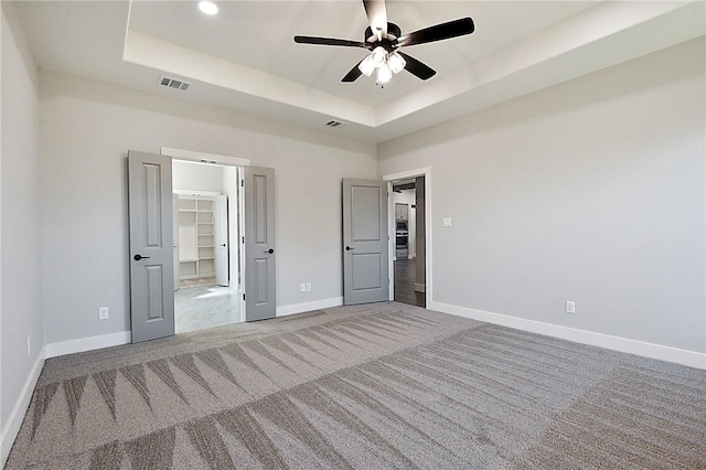 2803 Spector Dr, Bryan, TX 77808 - unfurnished bedroom featuring carpet, a tray ceiling, baseboards, a spacious closet, and ceiling fan