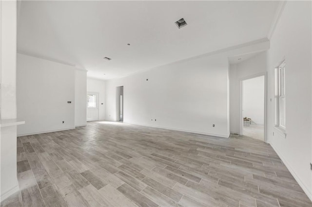 empty room with ornamental molding and light hardwood / wood-style flooring