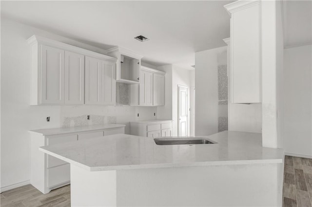 kitchen with kitchen peninsula, light hardwood / wood-style flooring, and white cabinetry