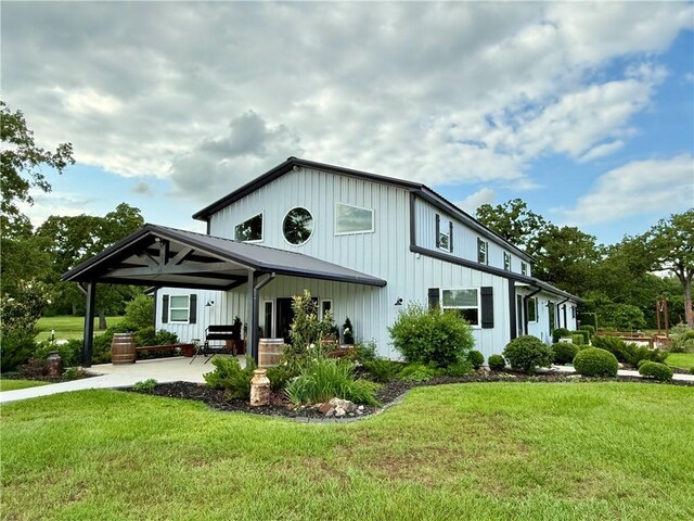 601 E Collard St, Madisonville, TX 77864 - view of front of home with a front yard, driveway, board and batten siding, and an attached carport
