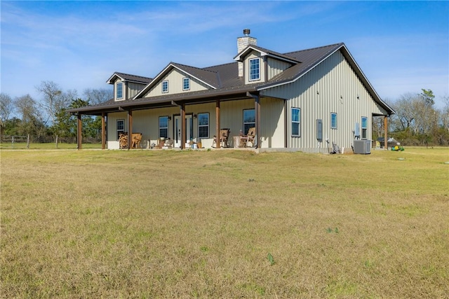 back of property with central AC, a lawn, and a chimney