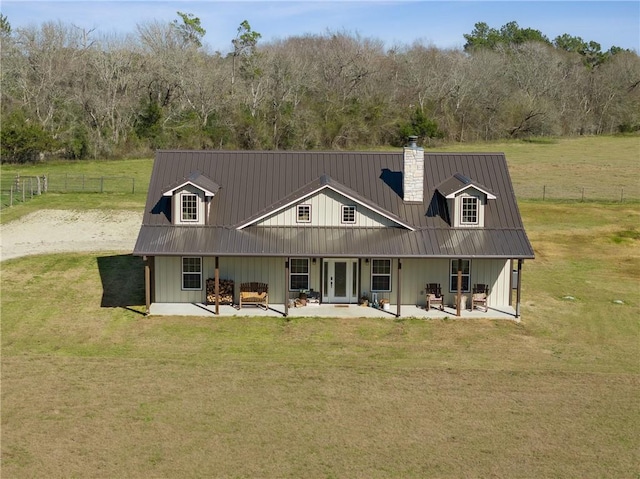 rear view of property featuring french doors, a patio area, a yard, and metal roof