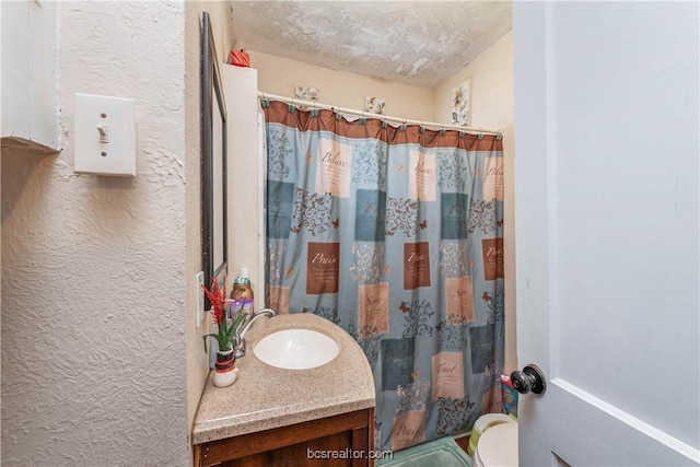 bathroom with vanity, curtained shower, toilet, and a textured ceiling