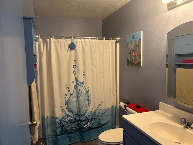 bathroom with vanity, toilet, and a textured ceiling