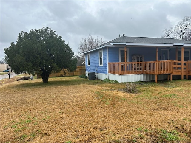 exterior space with a wooden deck, central AC unit, and a lawn