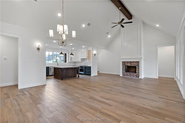 kitchen with appliances with stainless steel finishes, light wood-type flooring, pendant lighting, a fireplace, and a center island