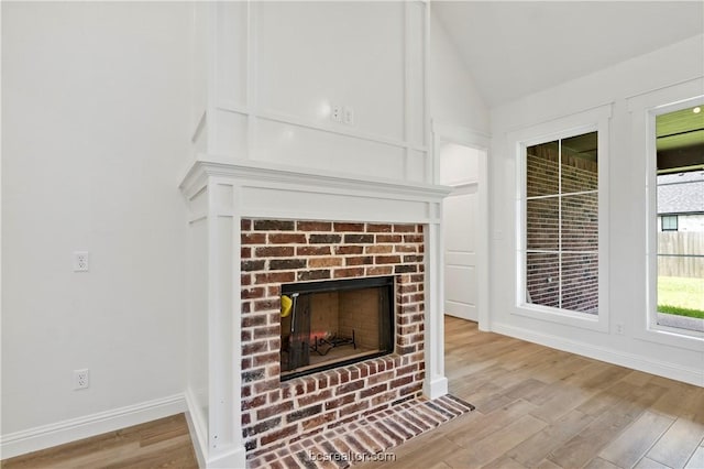 unfurnished living room with a fireplace, light hardwood / wood-style flooring, and lofted ceiling