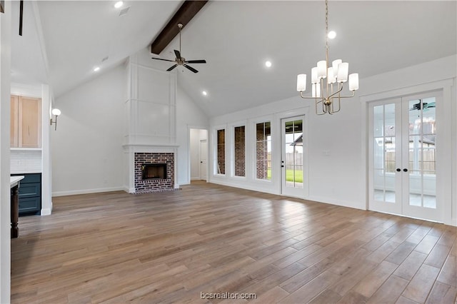 unfurnished living room with french doors, high vaulted ceiling, light hardwood / wood-style floors, a fireplace, and ceiling fan with notable chandelier