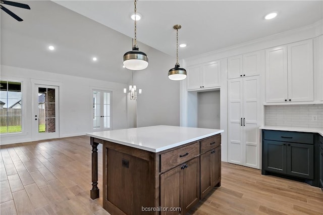 kitchen featuring ceiling fan with notable chandelier, light hardwood / wood-style flooring, decorative backsplash, decorative light fixtures, and white cabinetry