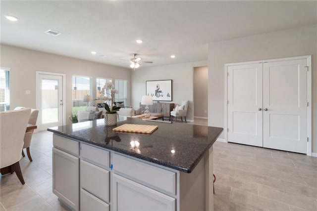 kitchen featuring recessed lighting, visible vents, open floor plan, a center island, and dark stone countertops