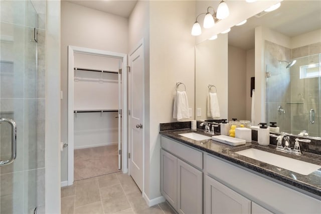 bathroom featuring double vanity, a sink, a walk in closet, and a shower stall