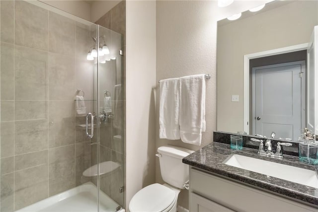 bathroom featuring toilet, a shower stall, and vanity