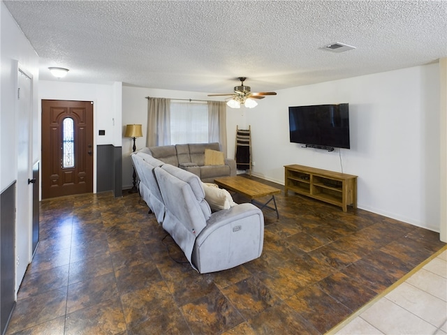 living room with ceiling fan and a textured ceiling