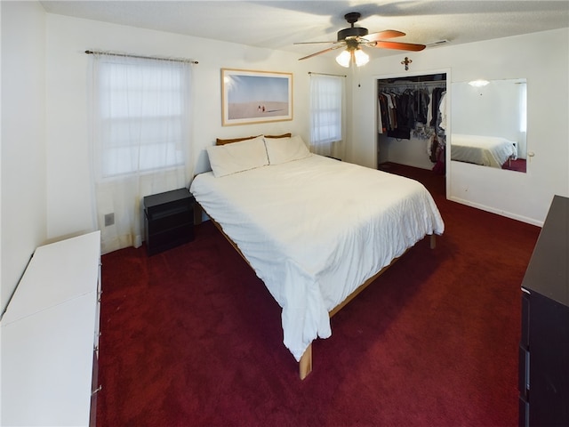 bedroom with multiple windows, ceiling fan, a closet, and dark carpet