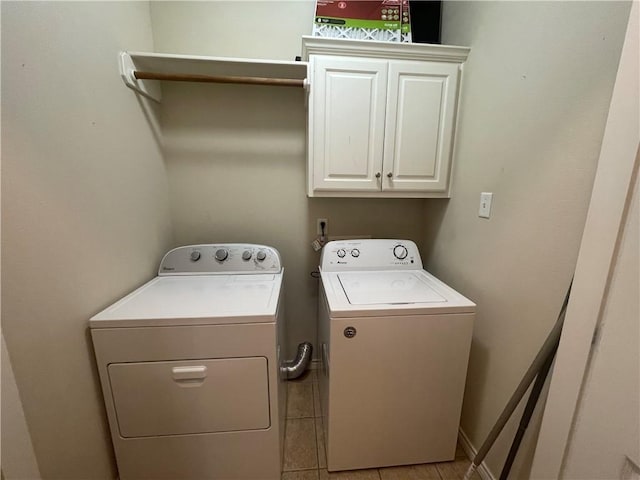washroom with washing machine and clothes dryer, light tile patterned floors, and cabinet space