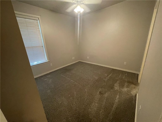 spare room with a ceiling fan, baseboards, and dark carpet