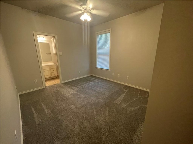 carpeted spare room featuring a ceiling fan and baseboards
