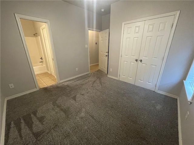 unfurnished bedroom featuring baseboards, ensuite bath, carpet flooring, and a closet