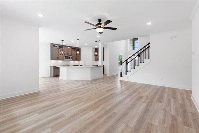 unfurnished living room with ceiling fan, light wood-type flooring, and crown molding