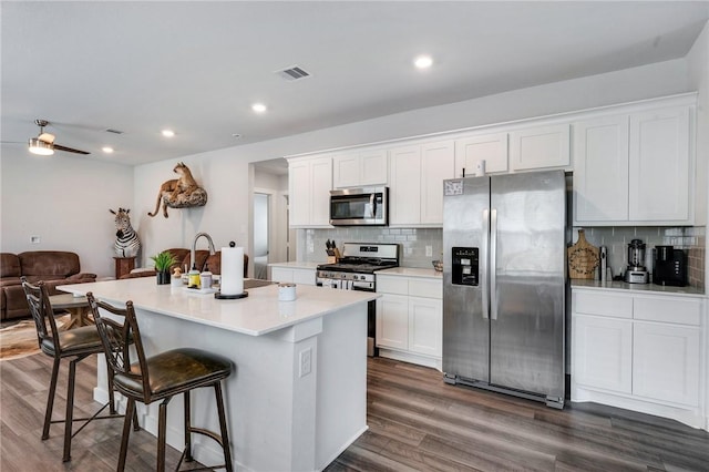 kitchen featuring white cabinetry, appliances with stainless steel finishes, a kitchen island with sink, and tasteful backsplash