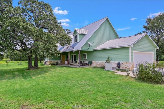 rear view of property featuring a garage and a lawn