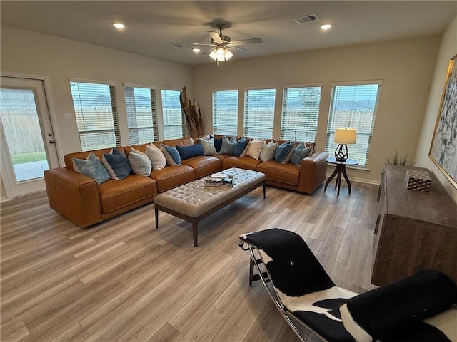 living room with a wealth of natural light, light hardwood / wood-style flooring, and ceiling fan