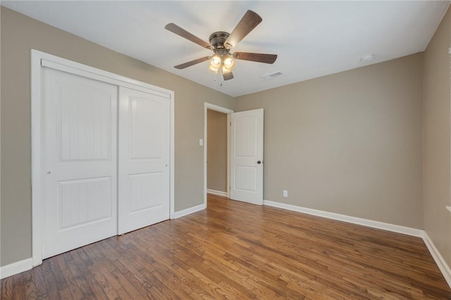 unfurnished bedroom with hardwood / wood-style flooring, ceiling fan, and a closet