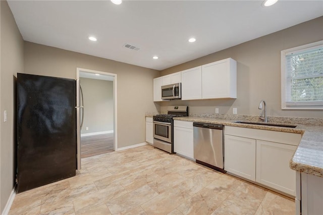 kitchen with light stone countertops, sink, white cabinets, and stainless steel appliances