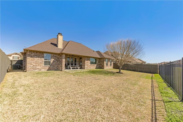 15658 Long Creek Ln, College Station, TX 77845 - rear view of property featuring brick siding, roof with shingles, a chimney, a lawn, and a fenced backyard