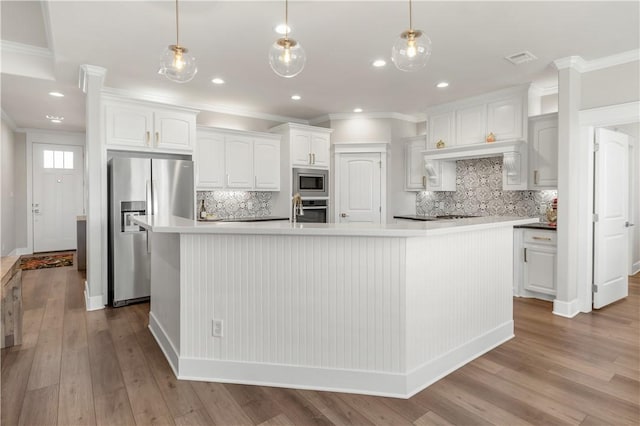 15658 Long Creek Ln, College Station, TX 77845 - kitchen with light wood-style flooring, stainless steel appliances, a spacious island, white cabinets, and ornamental molding