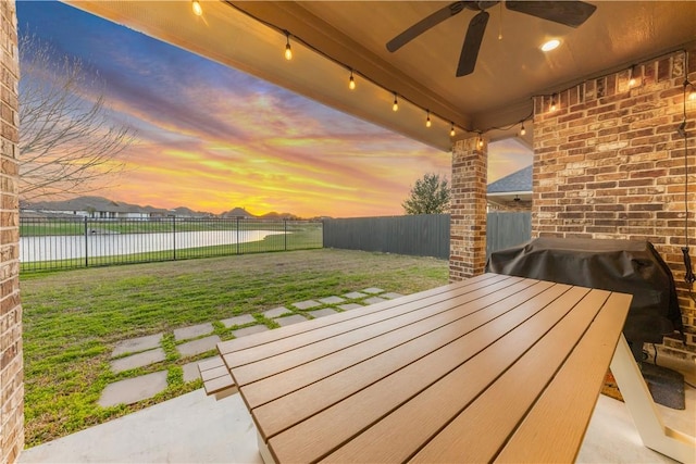 15658 Long Creek Ln, College Station, TX 77845 - patio terrace at dusk featuring a fenced backyard, ceiling fan, and a yard
